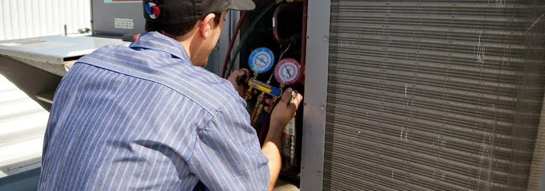 HVAC technician servicing a condenser unit in New Orleans