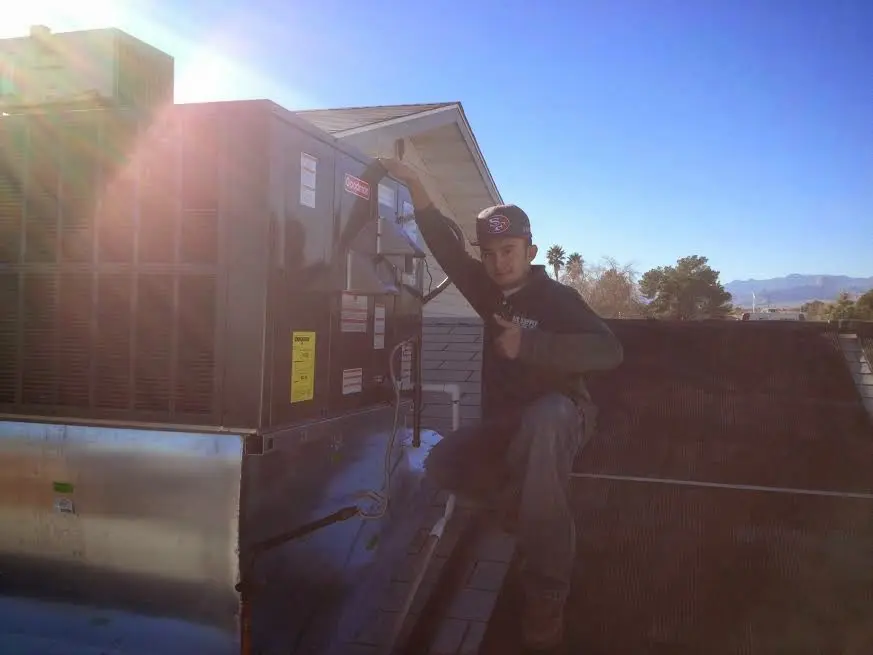 HVAC technician performing AC Tune-Up on a rooftop unit in New Orleans